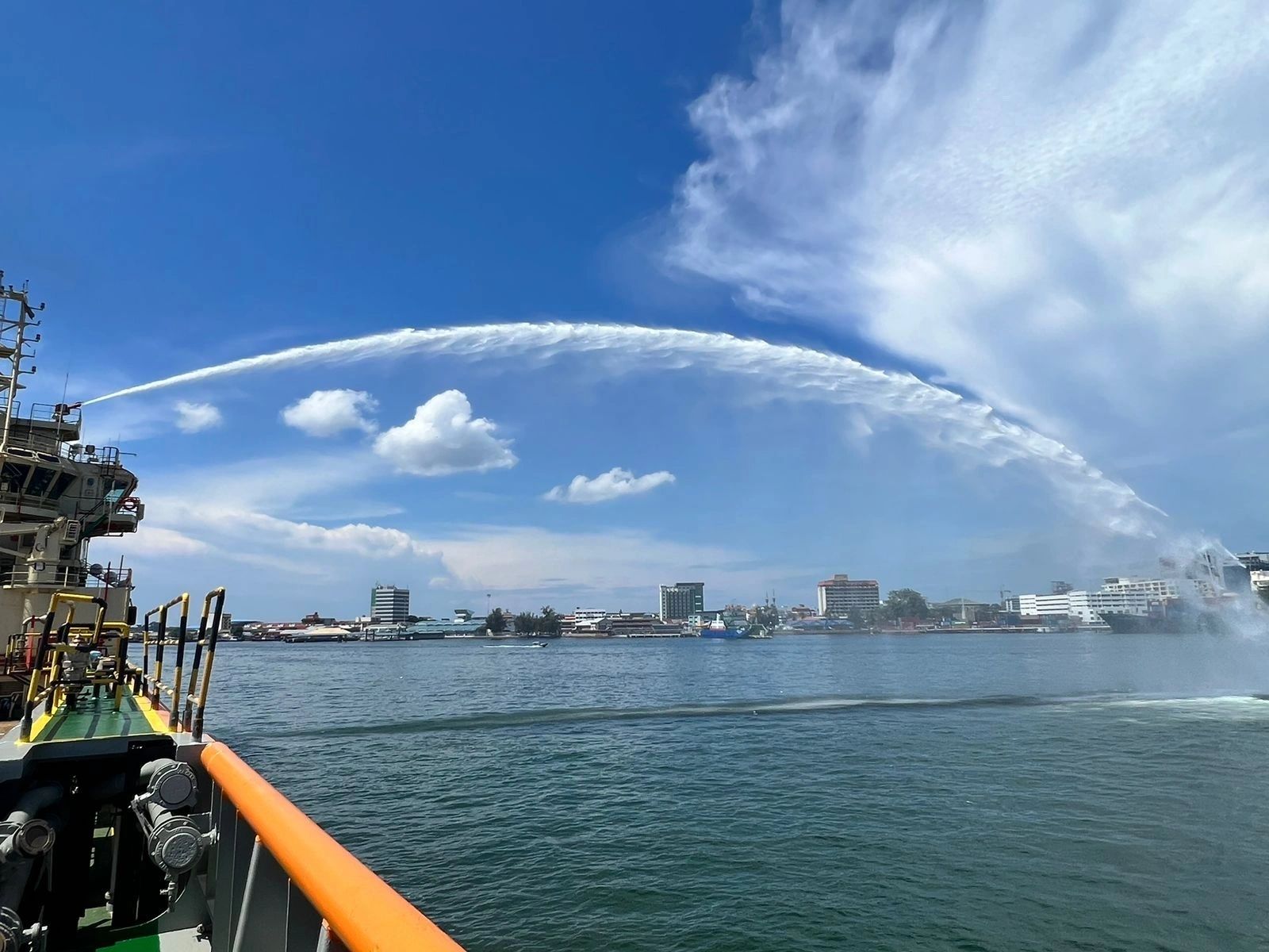 Naval vessel water spray harbor cityscape